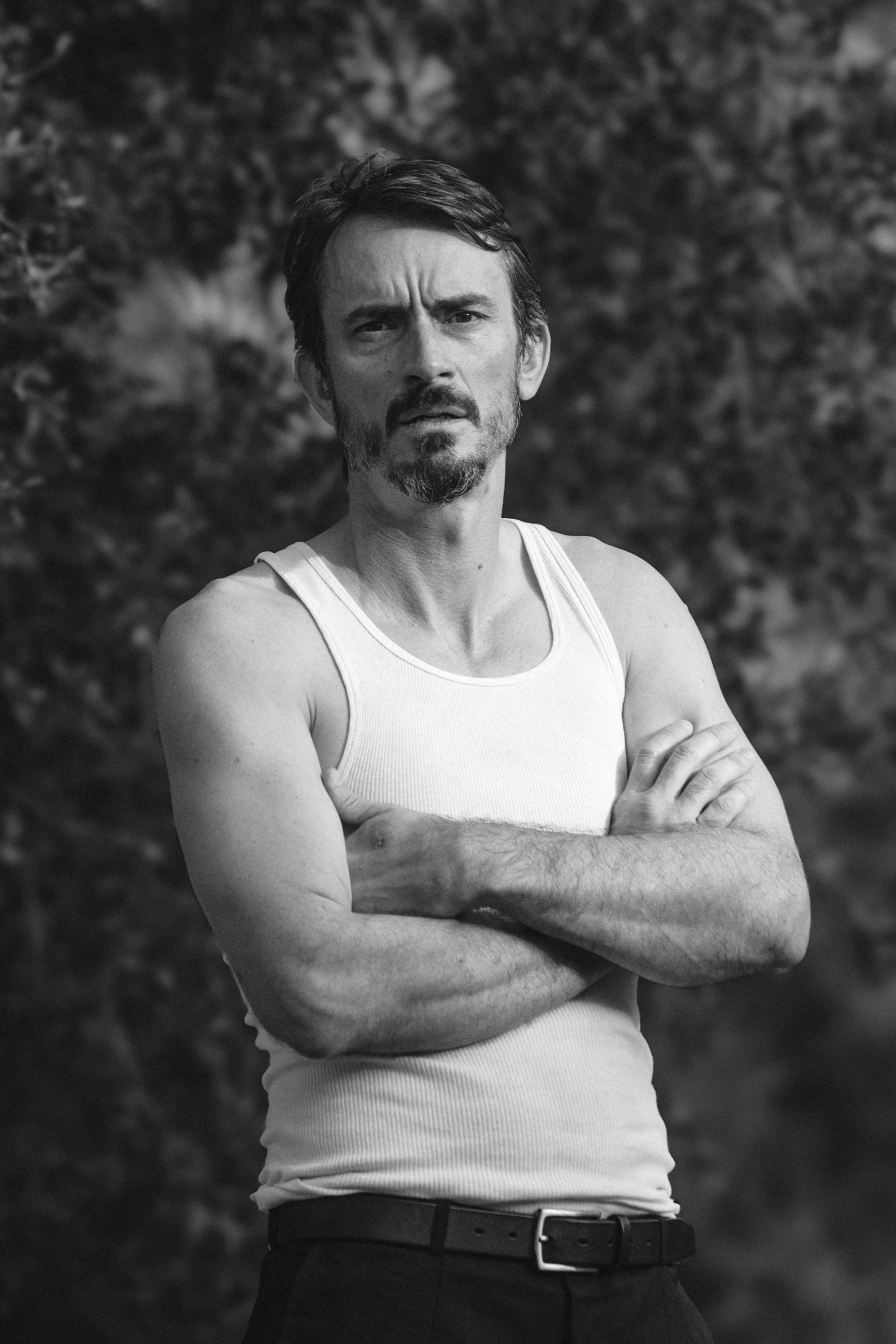 Black-and-white portrait of actor Luke Edwards, arms crossed